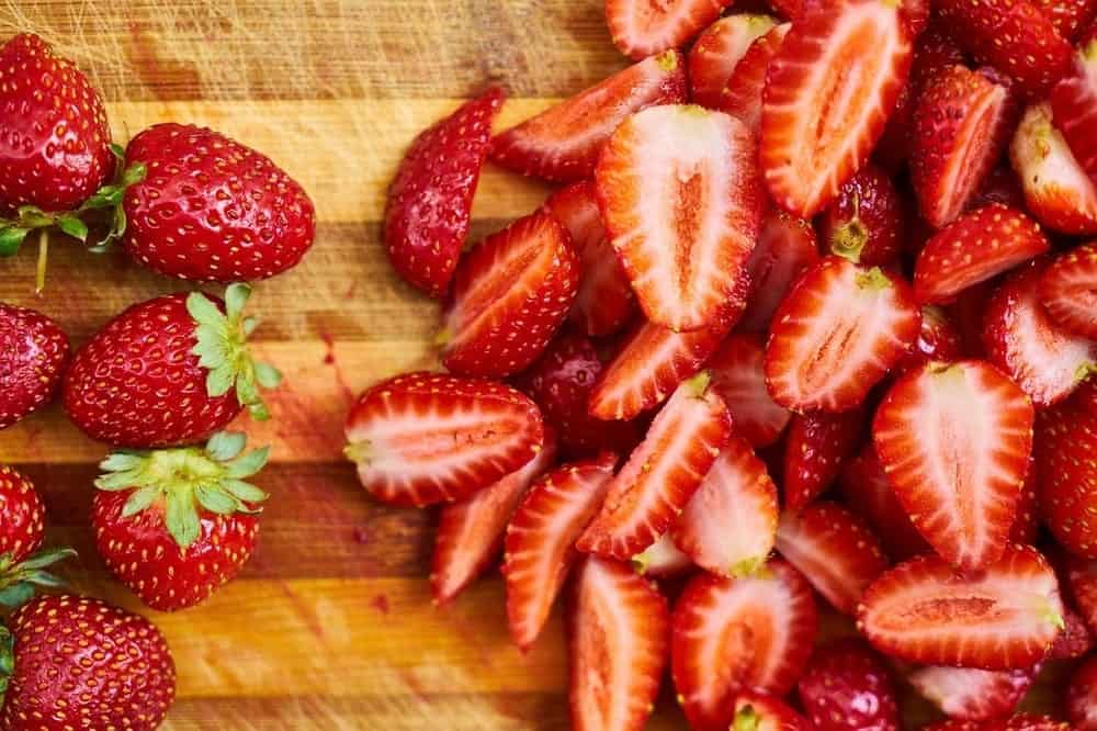 whole strawberries being sliced